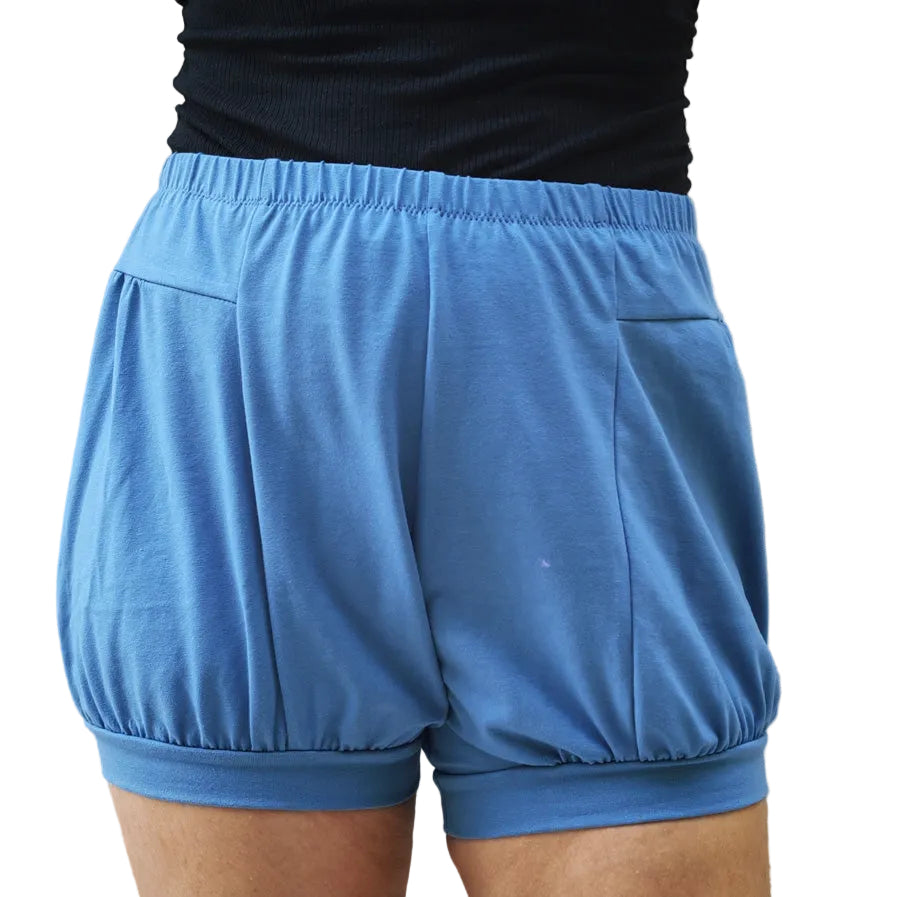 A close-up view of a person wearing light blue athletic shorts with a gathered elastic waistband and a matching elastic hem, paired with a black top.