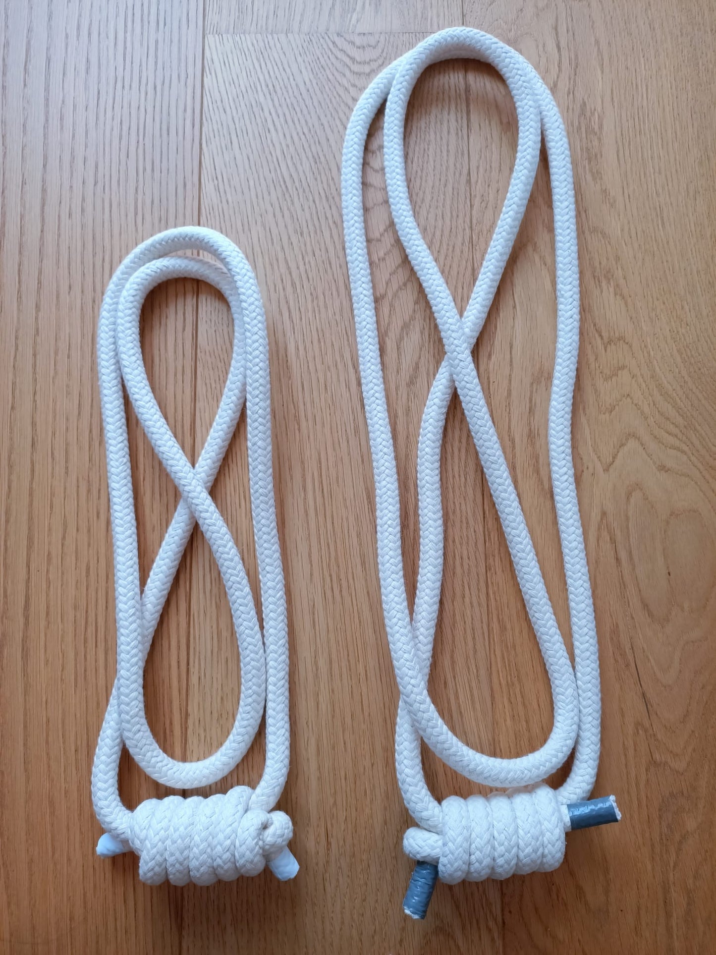 2 cuerdas de yoga iyengar de color blanco y de largo diferente en suelo de madera
