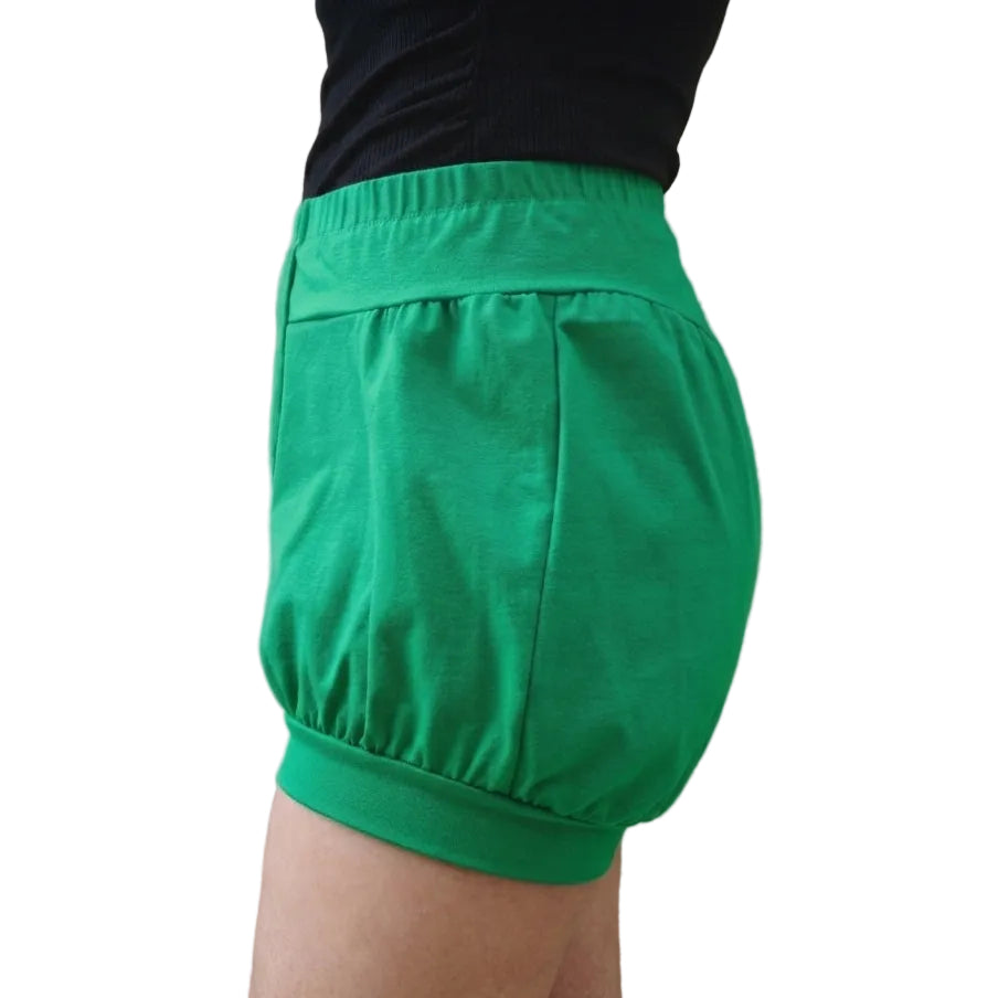 Bright green yoga bloomers with a gathered elastic waistband and hem, shown on a model from the side.