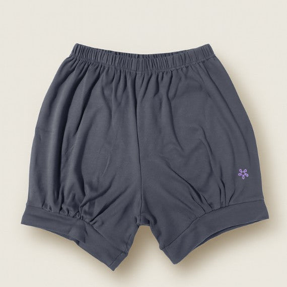 Dark gray yoga shorts with a small logo on a beige background
