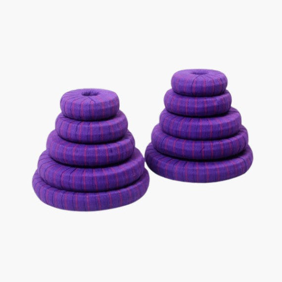 Set of purple iyengar yoga donuts stacked on a white background
