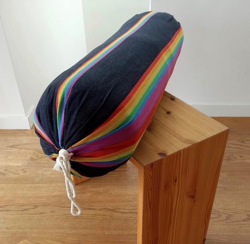 black and rainbow yoga bolster on wood halasana box