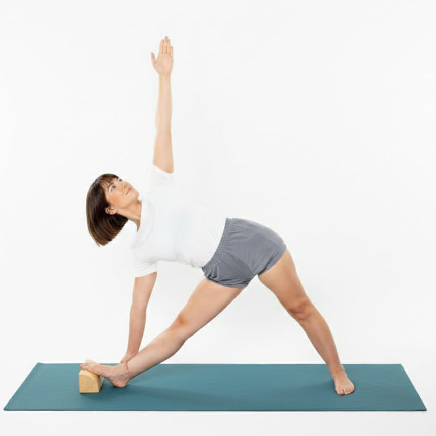 Woman performing trikonasana using a quarter round yoga prop under her foot