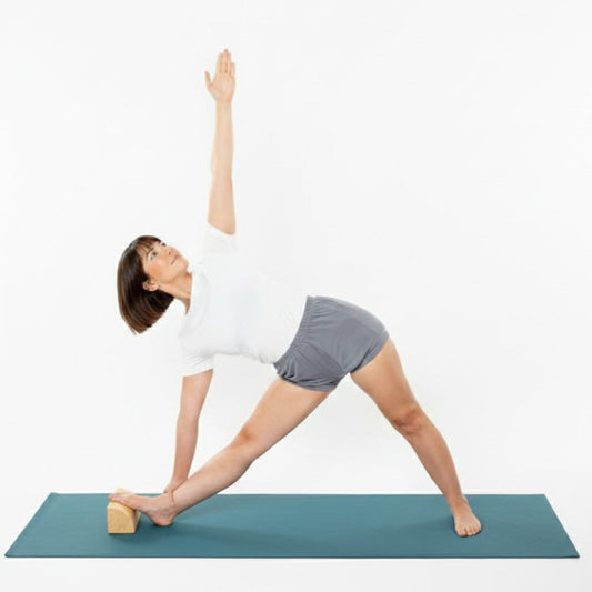 Woman performing trikonasana using a quarter round yoga prop under her foot