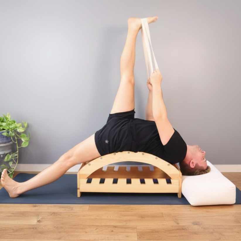 Person using a wood yoga backbend bench on a mat with a neutral background