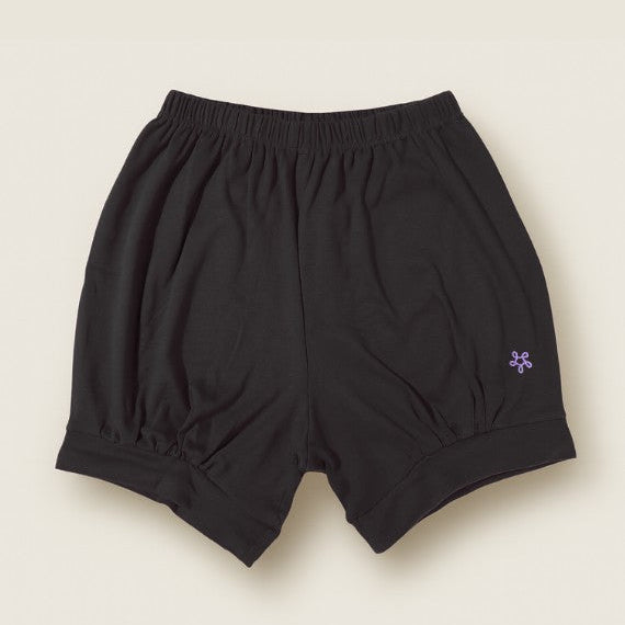 Black yoga shorts with a small logo on a beige background