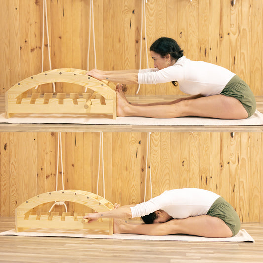 Person using a wooden yoga bench in forward bends in a wooden room.